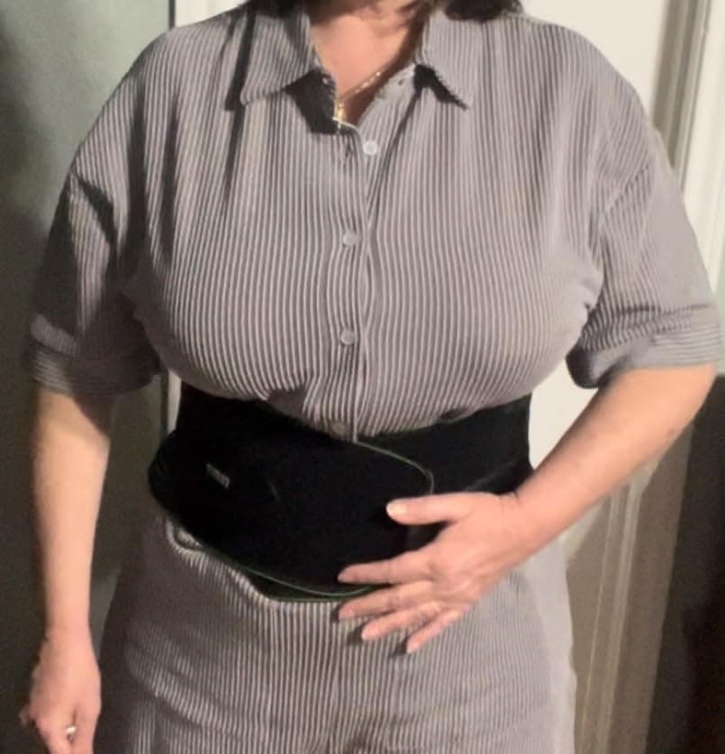 Customer wearing the Bracelite back support under a shirt, hand resting on side